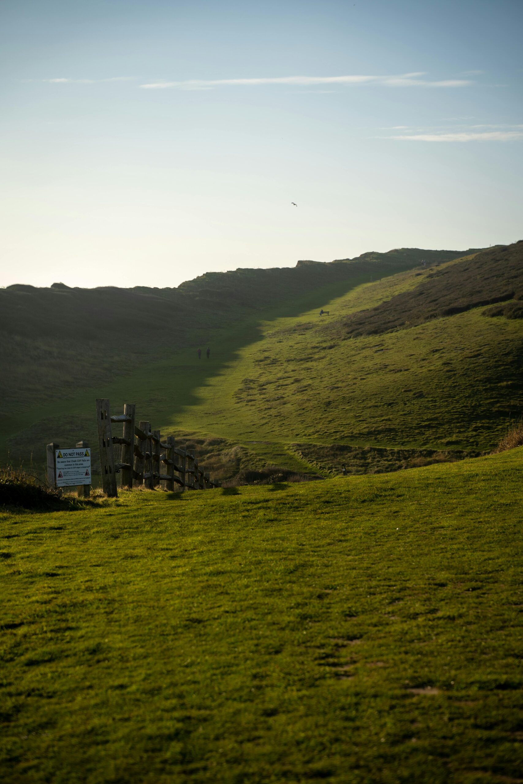 Scenic view of lush green hills and a rustic fence in Seaford, England at dawn.